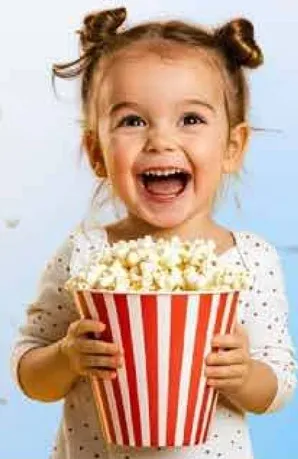 طفل سعيد يحمل دلوا كبيرا من الفشار.