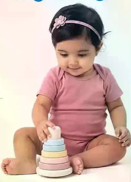 طفل لطيف يرتدي ملابس ورديه اثناء اللعب بلعبه التكديس.