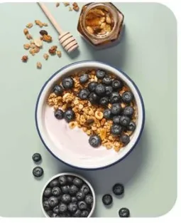 وعاء لذيذ من الزبادي مغطي بالجرانولا والتوت الطازج، مثالي لفطور صحي.