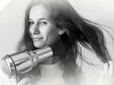 امراه تستخدم مجفف الشعر لتصفيف شعرها.